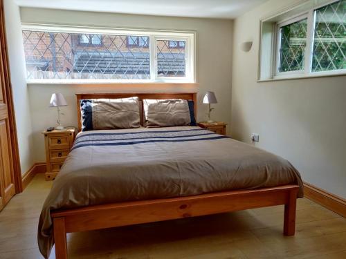 a bedroom with a large bed with two windows at Whitehouse Cottage - Great Paxton in Saint Neots