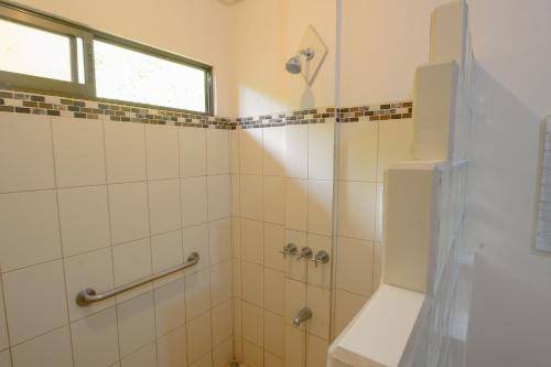 a bathroom with a shower with a toilet and a window at Hotel Cerro Lodge in Tarcoles