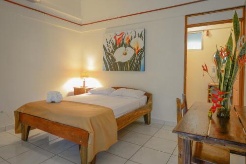 a bedroom with a bed and a table and a painting at Hotel Cerro Lodge in Tarcoles