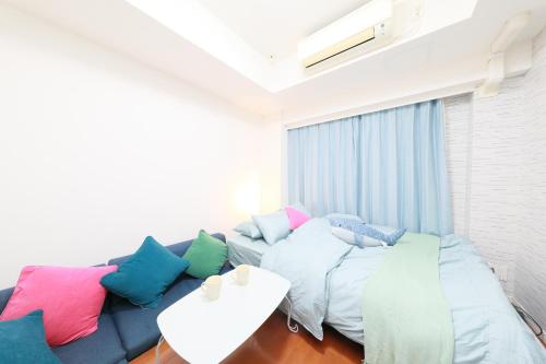 a living room with a blue couch with colorful pillows at IBASHO ShibuyaDogenzaka810 in Tokyo