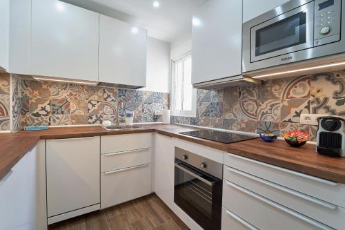 a kitchen with white cabinets and a microwave at El Coso Boutique Lucena in Lucena