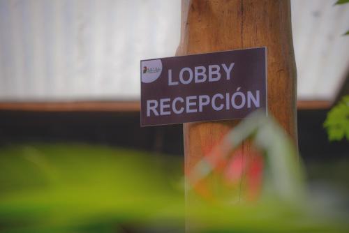 a sign on a pole that reads lobbey reception at Hotel Cerro Lodge in Tarcoles