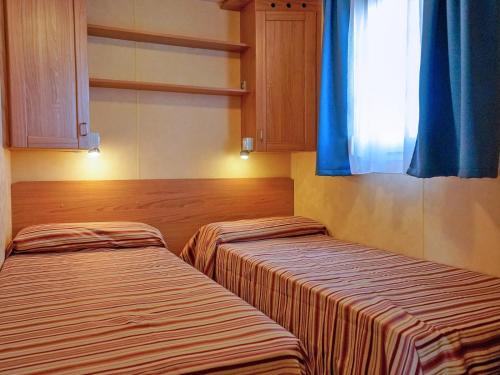 two beds in a room with a window at Portofelice Camping Village in Eraclea Mare