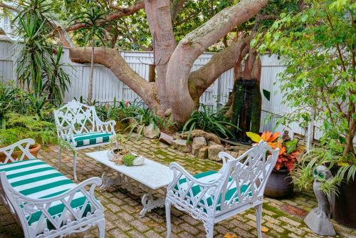 a patio with two chairs and a table and a tree at Moontide Riverside Lodge in Wilderness