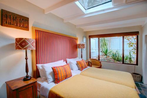 a bedroom with a bed with a lamp and a window at Moontide Riverside Lodge in Wilderness