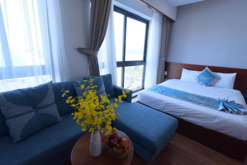 a living room with a bed and a couch with flowers at MENTO HOTEL QUY NHƠN in Quy Nhon