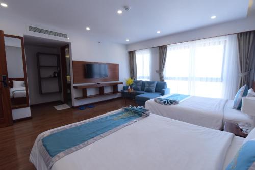 a hotel room with two beds and a couch at MENTO HOTEL QUY NHƠN in Quy Nhon