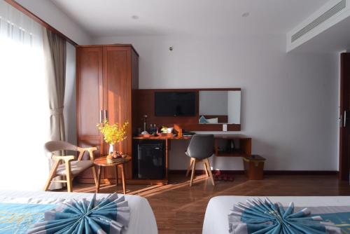 MENTO HOTEL QUY NHƠN في كوي نون: غرفة نوم بسرير ومكتب ومطبخ