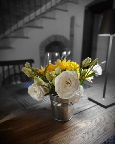 un jarrón con flores amarillas y blancas sobre una mesa en Millefiori Suite&Room, en Lago