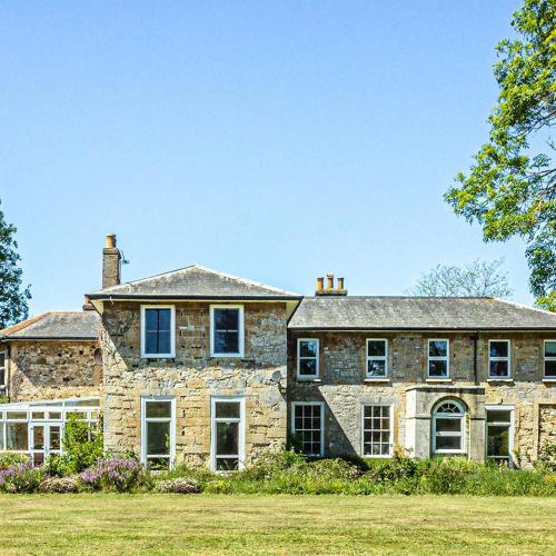 a large stone house with a grass yard at Cosy Wolf Bed & Breakfast in Freshwater