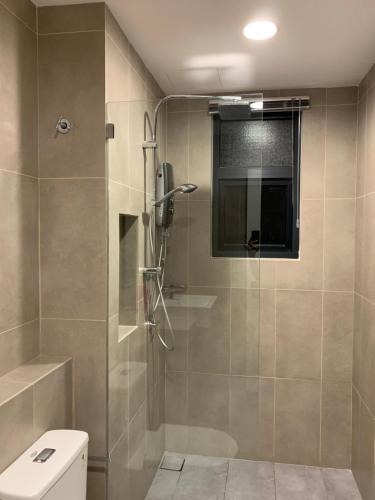 La salle de bains est pourvue d'une douche en verre et de toilettes. dans l'établissement Timurbay Seaview Suite by Guns Studio, à Kuantan