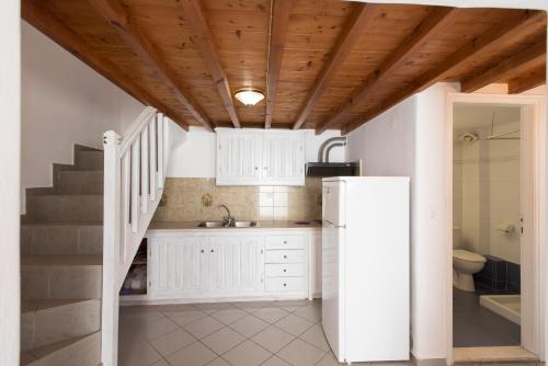 a kitchen with a white refrigerator and a staircase at Madres Houses in Mikonos