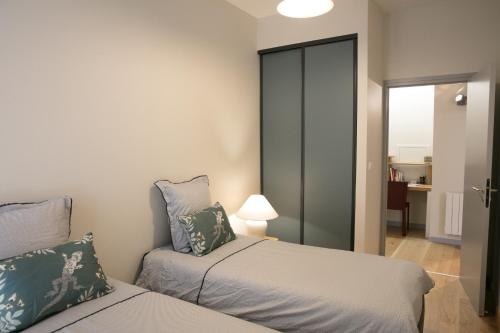a bedroom with two beds and a sliding glass door at Spacieux appartement, A-mi-chemin, au coeur de Tournus in Tournus