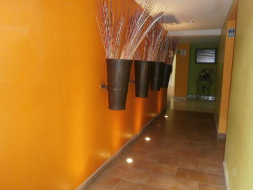 Un pasillo con tres macetas negras en la pared. en Hotel Anber, en Dolores Hidalgo