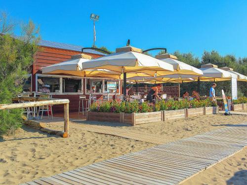 a restaurant with tables and umbrellas on the beach at Portofelice Camping Village in Eraclea Mare