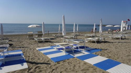 a beach with blue and white chairs and umbrellas at Portofelice Camping Village in Eraclea Mare