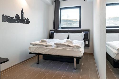 1 dormitorio con 1 cama con sábanas blancas y ventana en Augustus Hotel Bernkastel - Comfortable Budget Hotel en Bernkastel-Kues