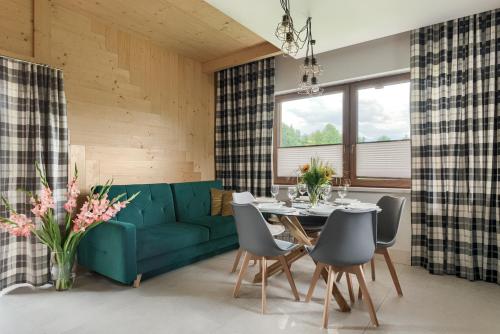 een woonkamer met een groene bank en een tafel en stoelen bij Domki Górskie Widoki in Biały Dunajec