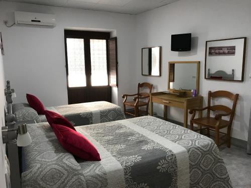 a bedroom with two beds and a table and a mirror at La Casa en el Centro in Écija