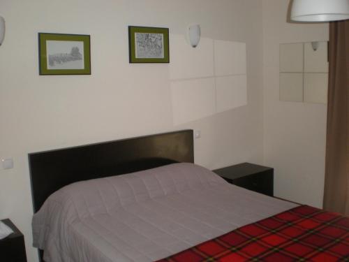 a bedroom with a bed and two pictures on the wall at Casa do Linhar - Quintas de Sirlyn in Tondela