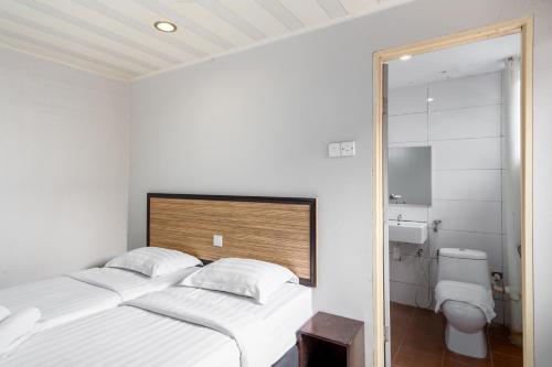 a white bedroom with two beds and a toilet at Subang Park Hotel in Subang Jaya