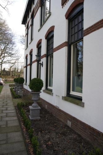 a white house with windows and a sidewalk at Bed & Breakfast Rijsterbosch in Rijs