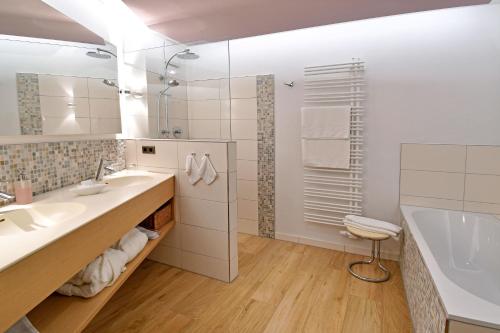 a bathroom with two sinks and a tub and a shower at Hotel & Weinhaus Anker in Marktheidenfeld