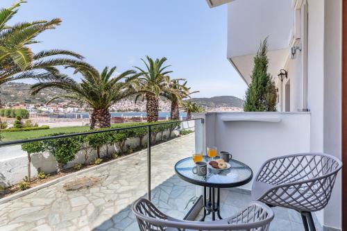a balcony with a table and chairs and palm trees at Olia Green Residence in Skopelos Town