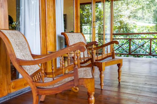 three wooden rocking chairs sitting on a porch at Pepper Trail in Sultan Bathery