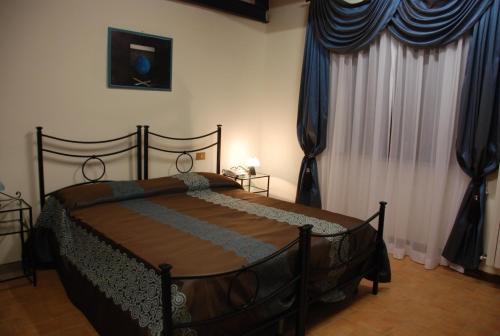 1 dormitorio con 1 cama grande y cortinas azules en Palazzo Bonfranceschi, en Belforte del Chienti