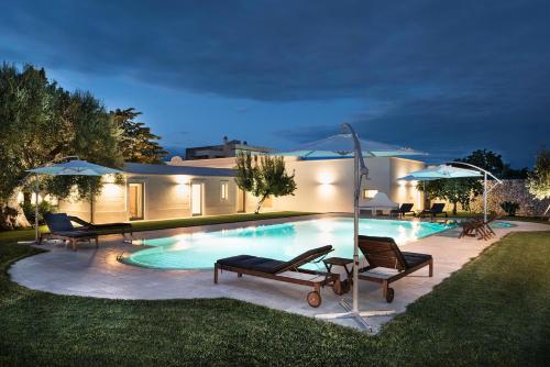 Una piscina con sillas y sombrillas al lado de una casa. en Masseria Il Mandorlo Fiorito x 8 Piscina Privata, en Ceglie Messapica