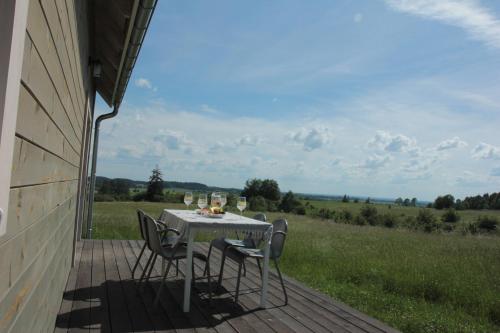 a table and chairs on a porch with a view of a field at Mazury Garbate - Dom I przy Cisowym Jarze in Kowale Oleckie