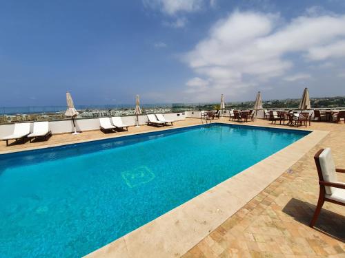 a beach with a pool, chairs, and a large swimming pool at Farah Rabat in Rabat