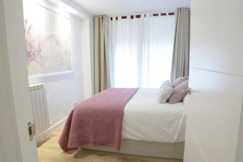 a white bedroom with a bed with a window at VUT La Casa de las Flores in Ávila