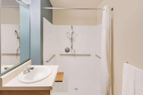 a white bathroom with a sink and a shower at WoodSpring Suites Council Bluffs in Council Bluffs