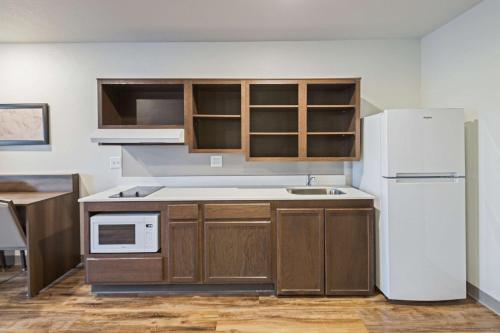 a kitchen with wooden cabinets and a white refrigerator at WoodSpring Suites Davenport Quad Cities in Davenport