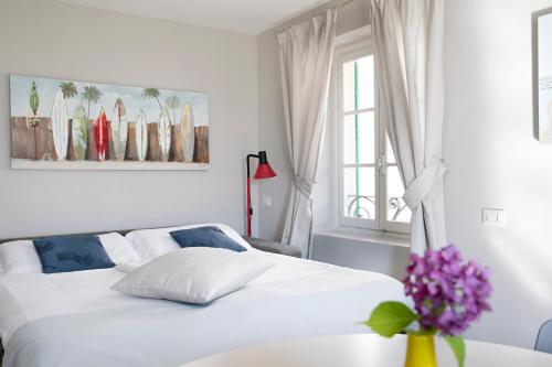 Un dormitorio blanco con una cama y un jarrón con flores púrpuras en Borgo Antico, en Luino