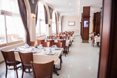 a dining room with tables and chairs and windows at Jewel Port Said Hotel in Port Said