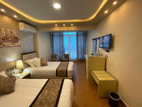 a hotel room with two beds and a television at Jewel Port Said Hotel in Port Said