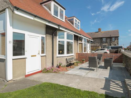 a house with a white door and some chairs at Hazonleigh in Seahouses