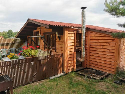 a small wooden shed with a fence in a yard at SP camping Spāres Prieduļi in Nīca