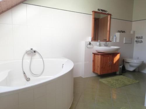 a white bathroom with a tub and a sink at Wohnung Elli in Kumhausen