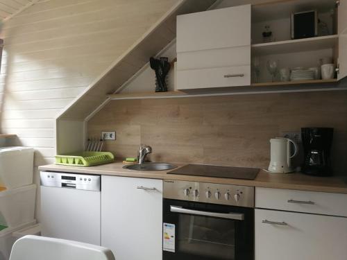 a kitchen with white cabinets and a sink and a stove at Wohnung Elli in Kumhausen
