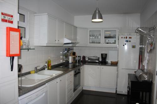 a white kitchen with a sink and a refrigerator at Vista Mar in Caniço