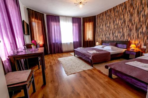 a bedroom with two beds and purple curtains at Casa Adalmo in Sighişoara