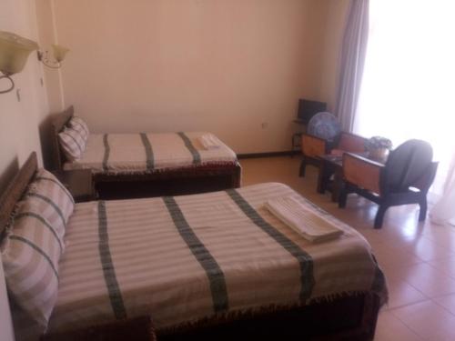 a room with two beds and a chair and a desk at Honey Land Hotel Lalibela in Lalībela