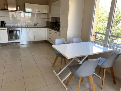 - une cuisine avec une table et des chaises blanches dans l'établissement La Villa Fréjus-Plage, à Fréjus