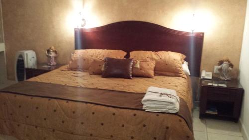 un dormitorio con una cama grande con cabecero de madera en Hotel Anber, en Dolores Hidalgo