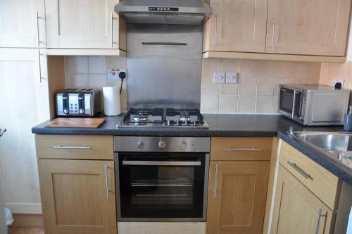 a kitchen with a stove top oven next to a sink at Modern Home just off Glastonbury High Street in Glastonbury