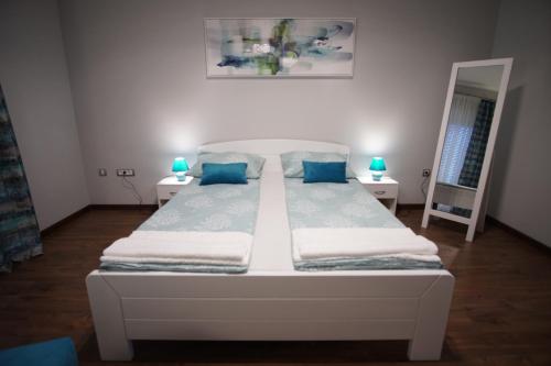 a white bed in a room with two mirrors at Marija in Srbobran